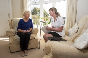 caregiver on a home visit talking to an elderly female patient