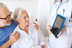 doctor showing a tablet pc to and old couple